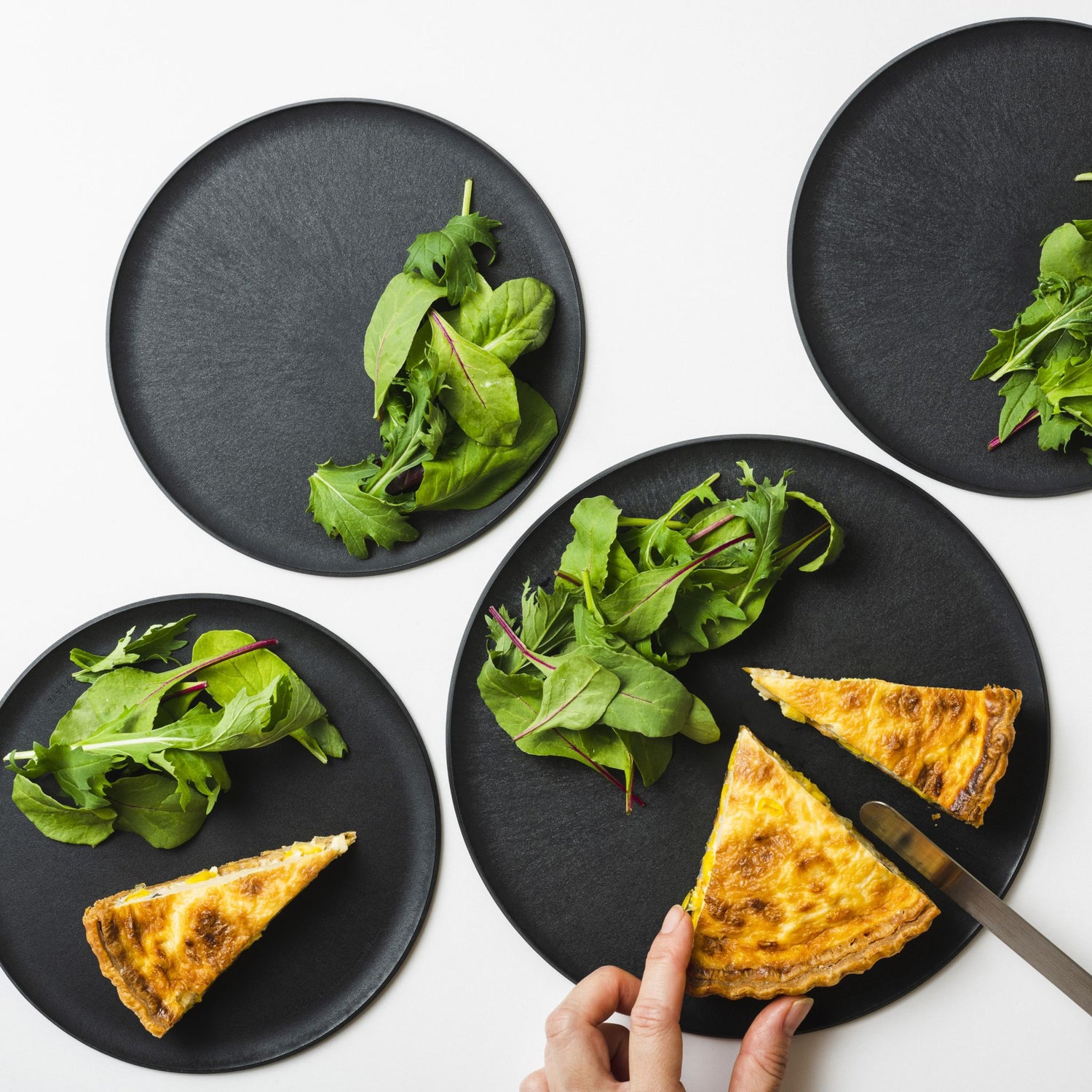 Plating quiche and salad on a CHOPLATE, showing its versatility from kitchen preparation to dining table.