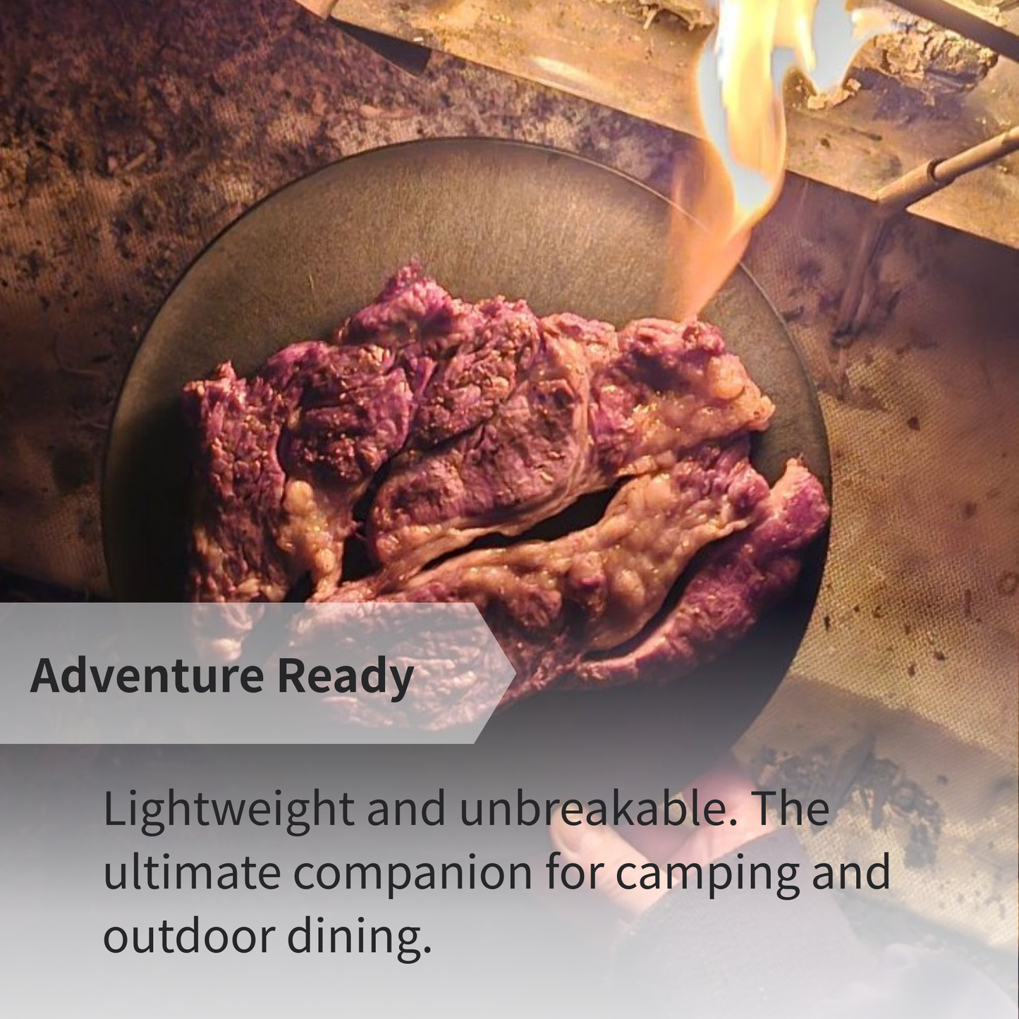 A steak served on a CHOPLATE near a campfire, highlighting its use as a durable camping cutting board plate.